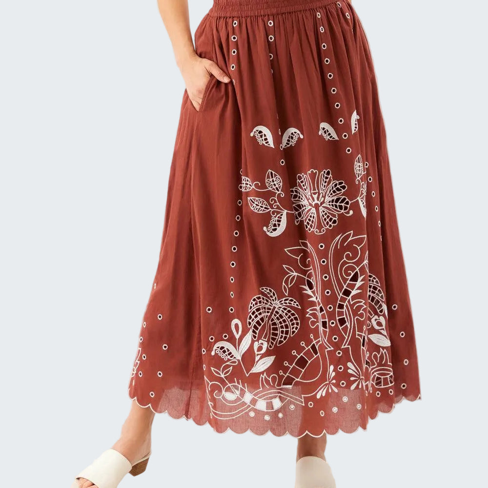 Brown skirt with white floral patterns worn by a person on a white background