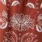 A close-up of a red patterned fabric with white floral or ornamental motifs.