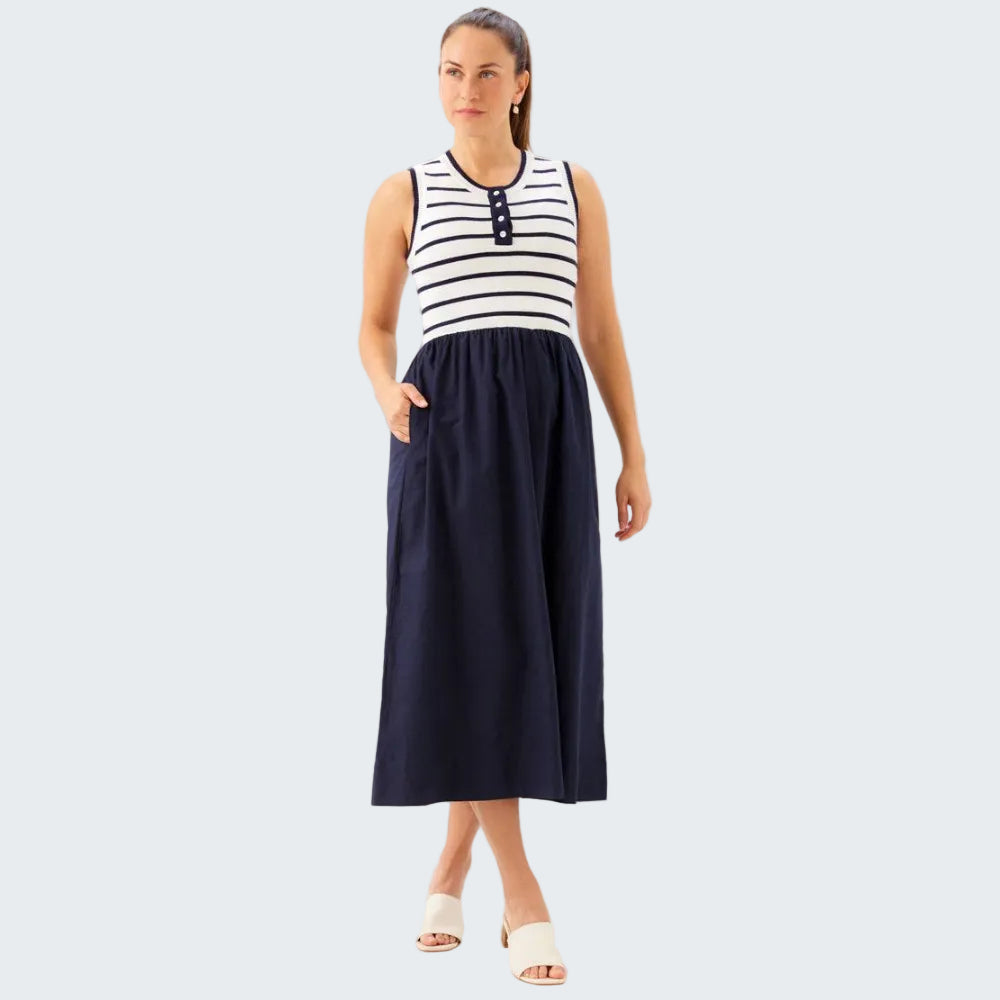 Woman wearing a black and white striped sleeveless top with a long navy skirt on a white background