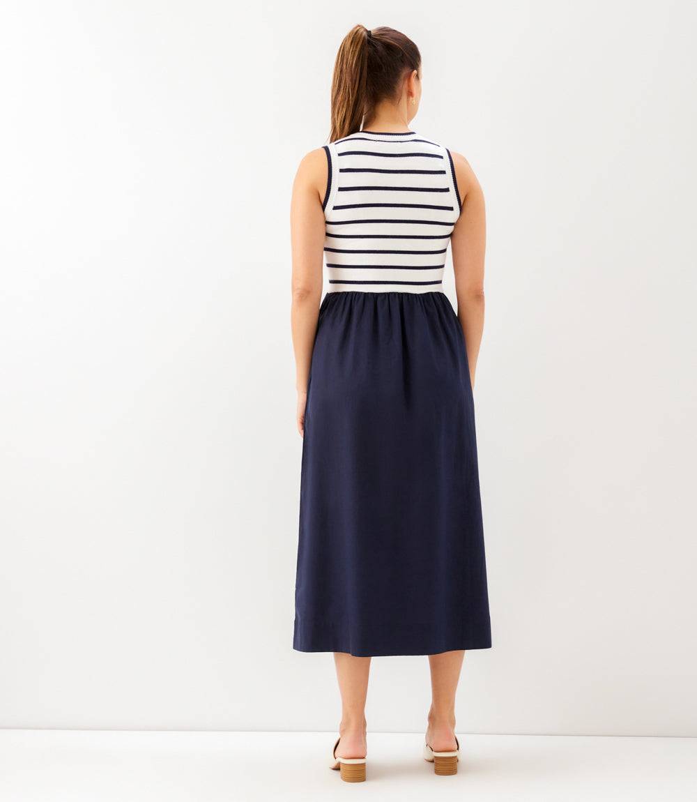Woman wearing a striped sleeveless top and navy skirt on a white background