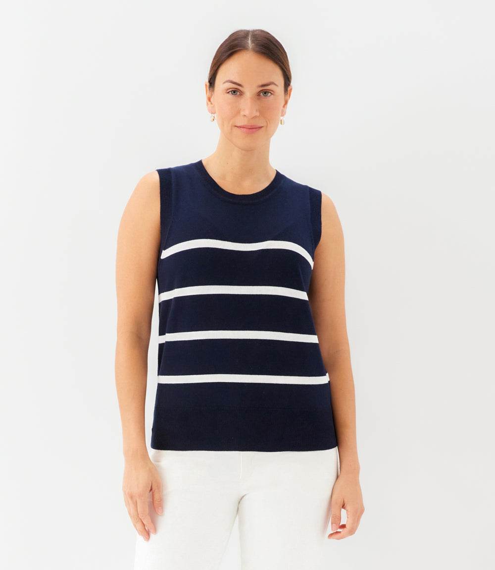 Woman wearing a navy sleeveless top with white stripes on a white background