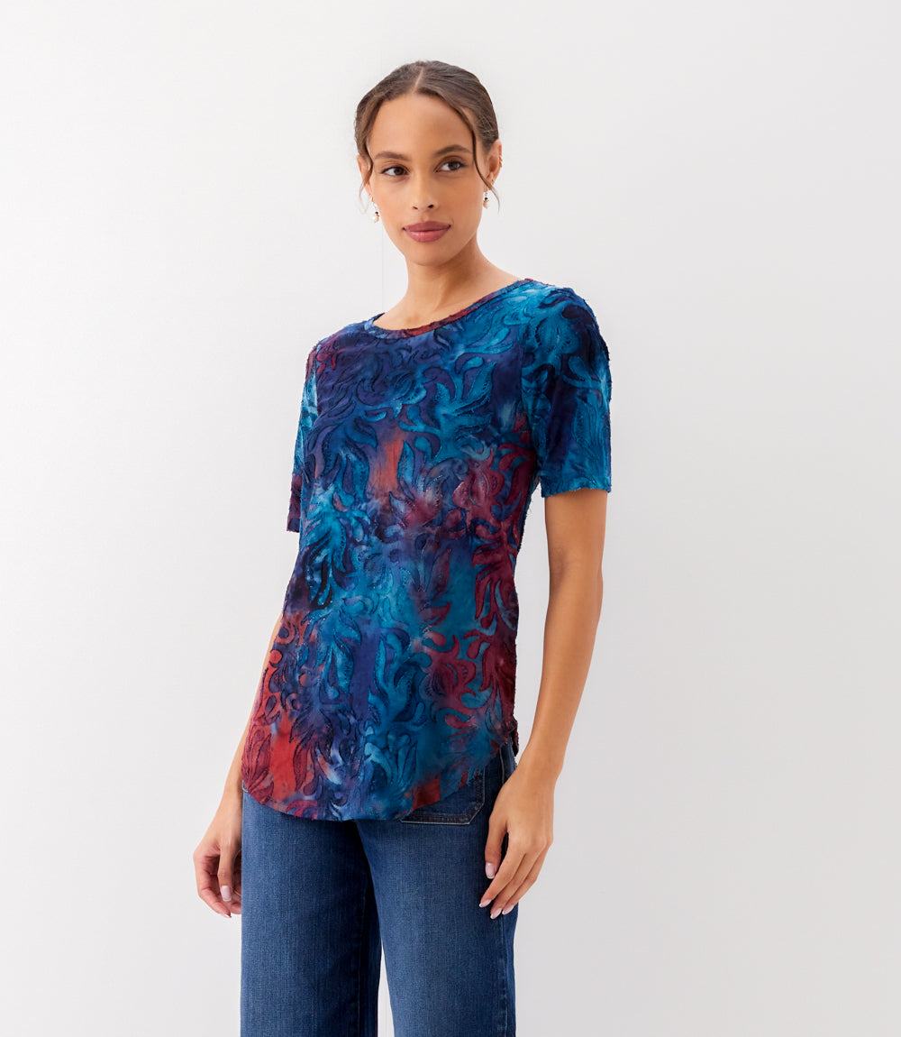 Woman wearing a colorful tie-dye shirt on a white background