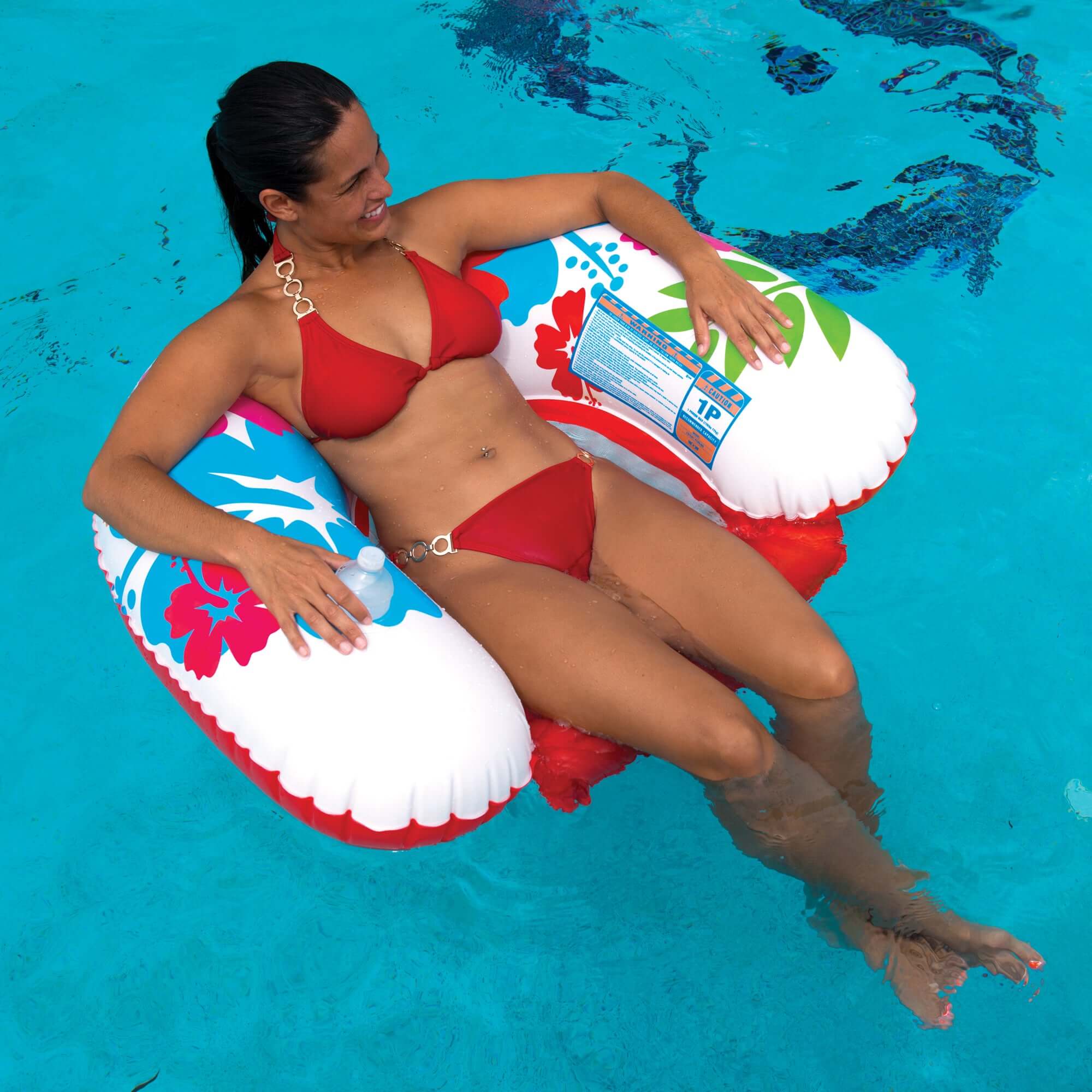 Woman in red bikini sitting on a colorful inflatable tube in a pool
