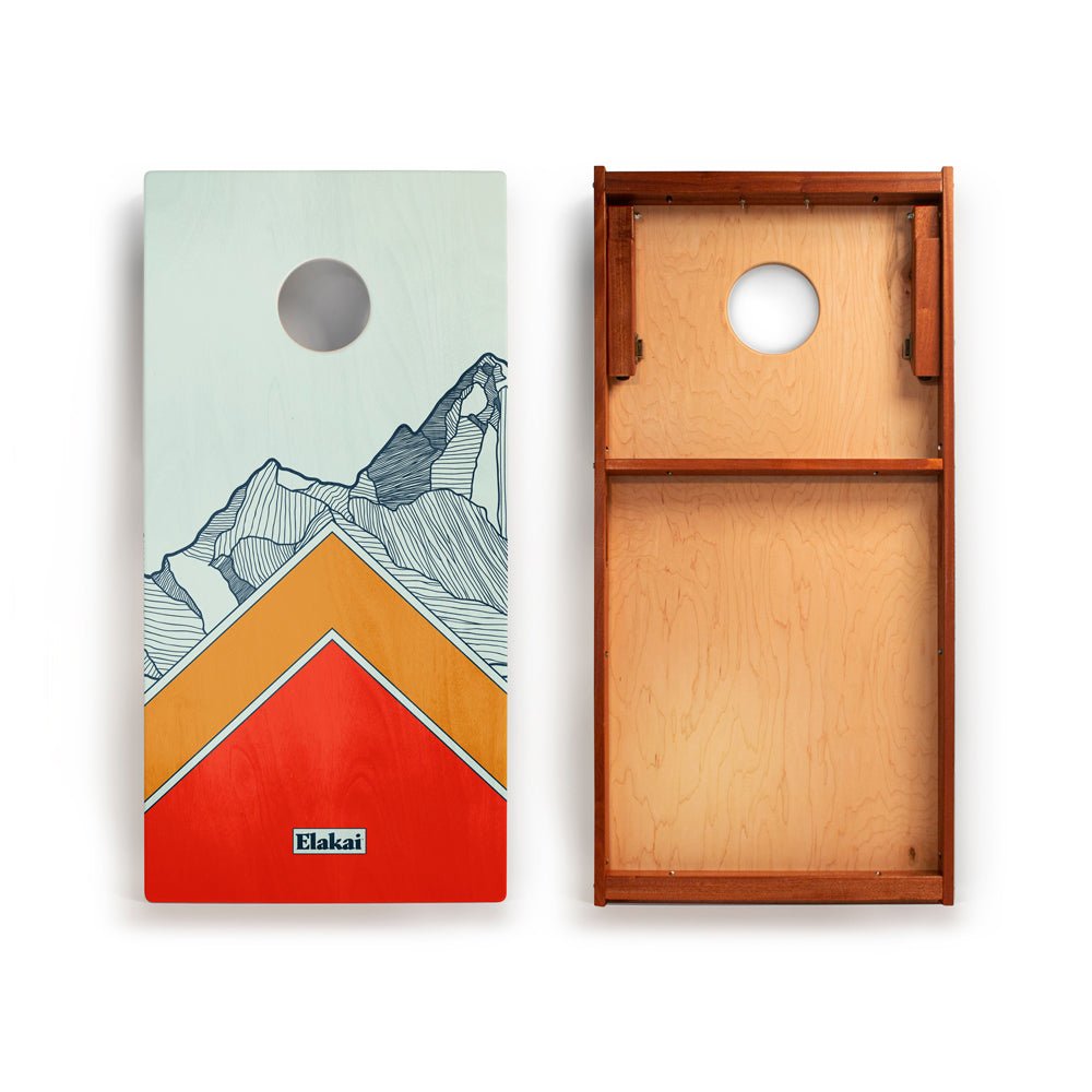 Cornhole board with mountain design on one side and wooden back on the other, featuring the Blakai brand.
