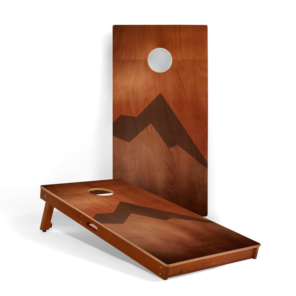 Wooden cornhole board with mountain design on a white background