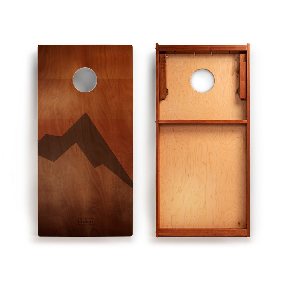 Wooden cornhole board with mountain design on a white background