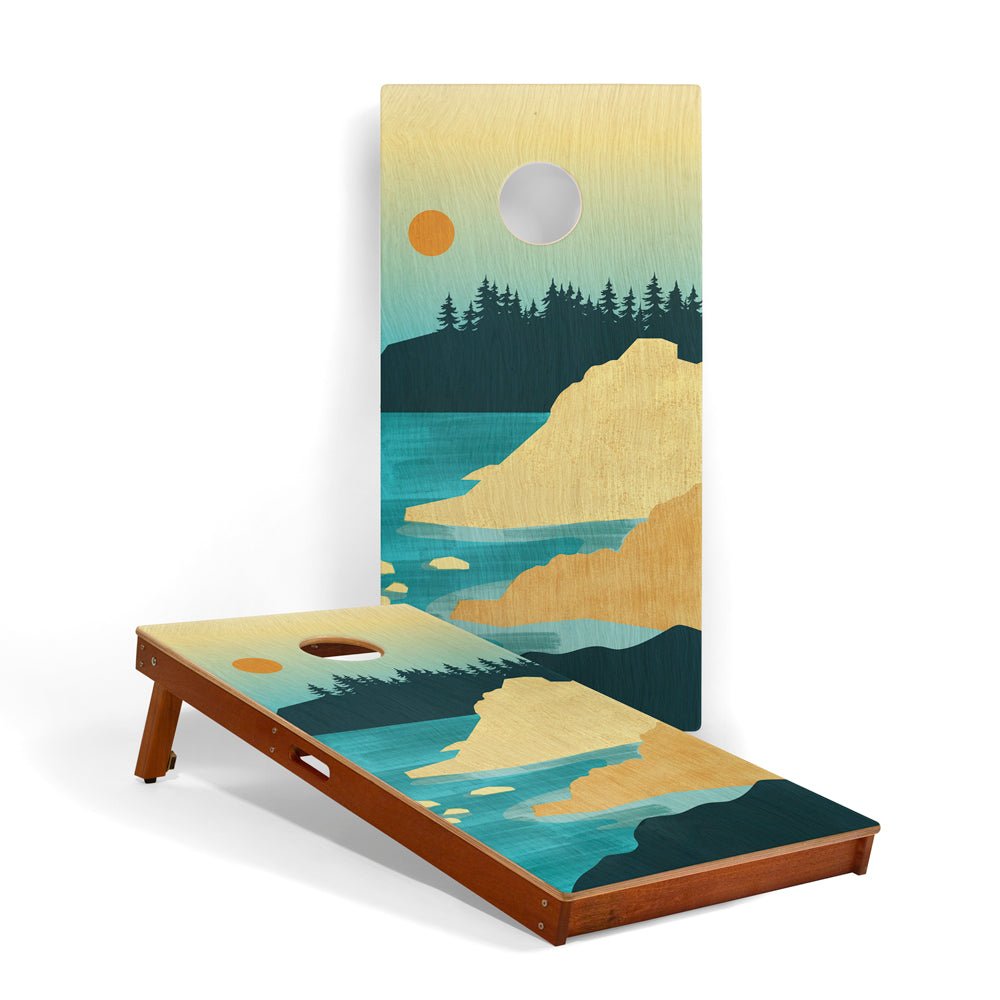 Cornhole board with a scenic design of mountains and water on a white background
