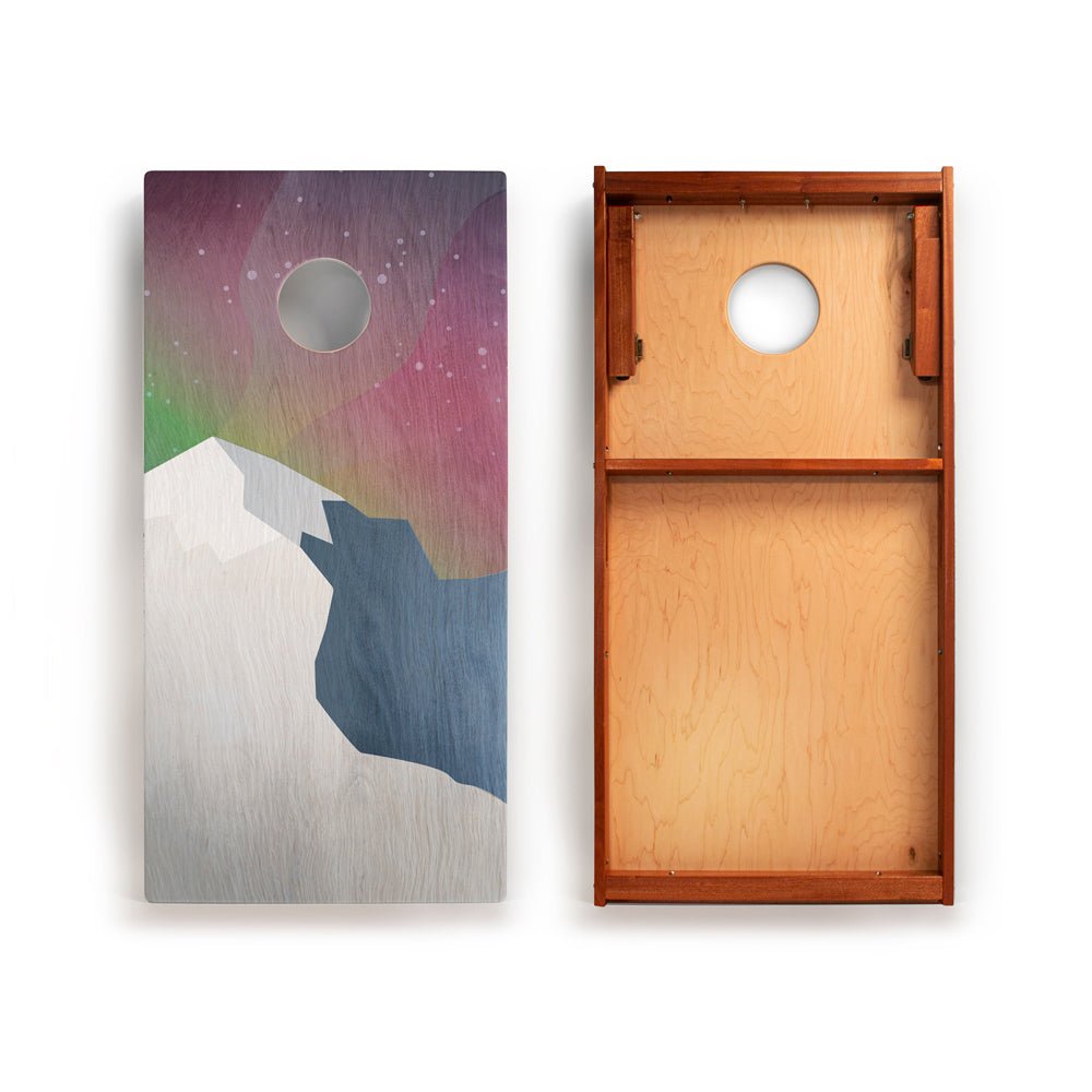 Cornhole board with mountain and starry sky design on one side and wooden texture on the other.