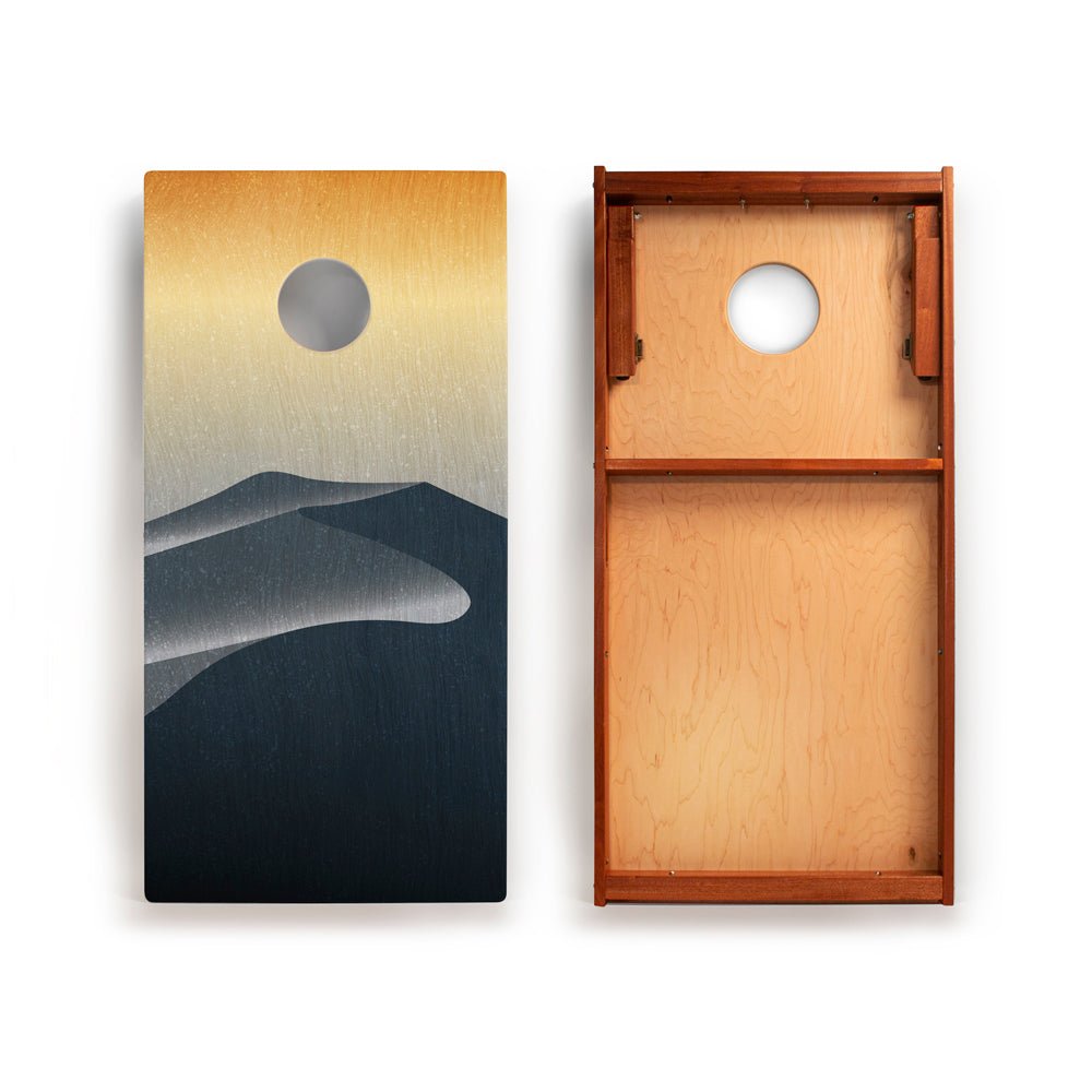 Cornhole board with mountain and moon design on one side and plain wood texture on the other.