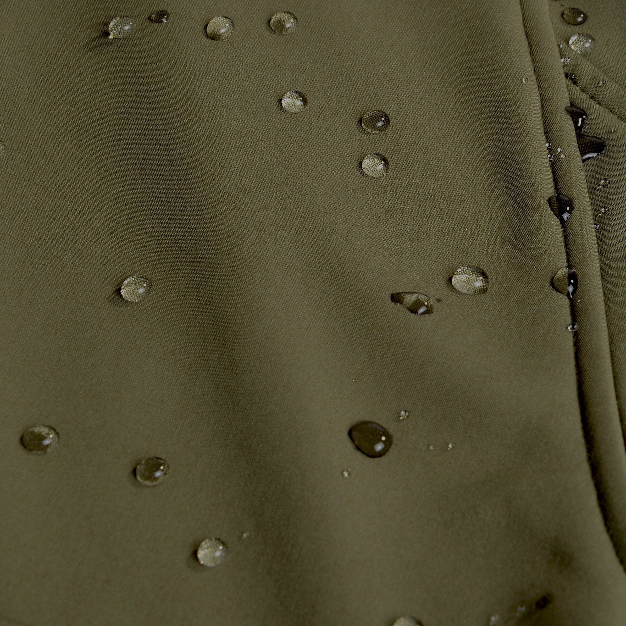 Close-up of a green fabric surface with embedded stones.