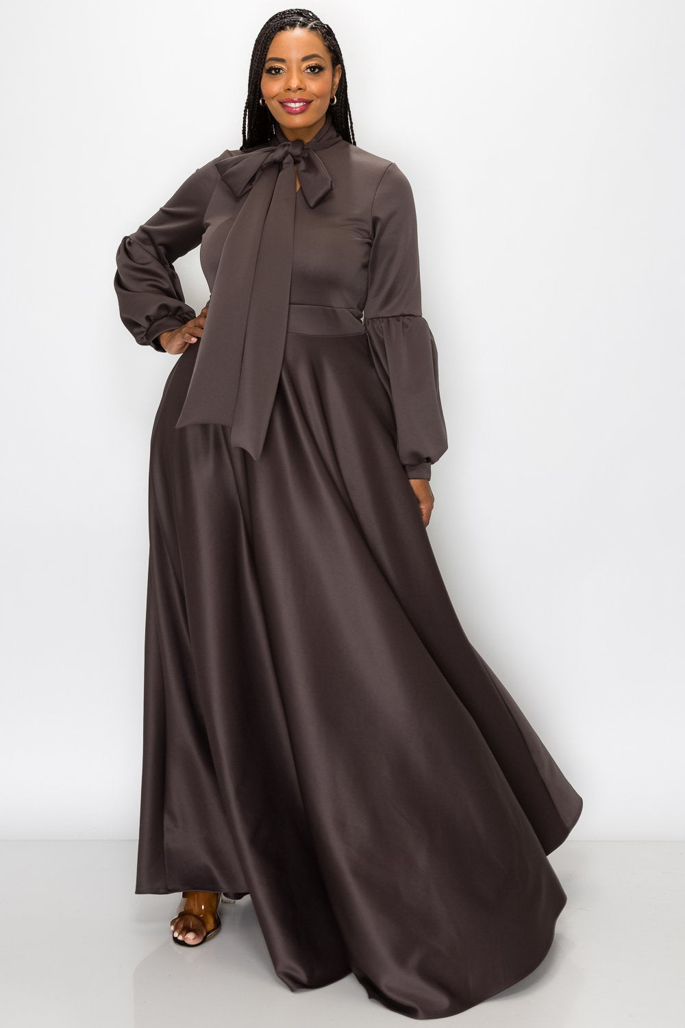 Woman wearing a long brown dress with a matching top on a white background