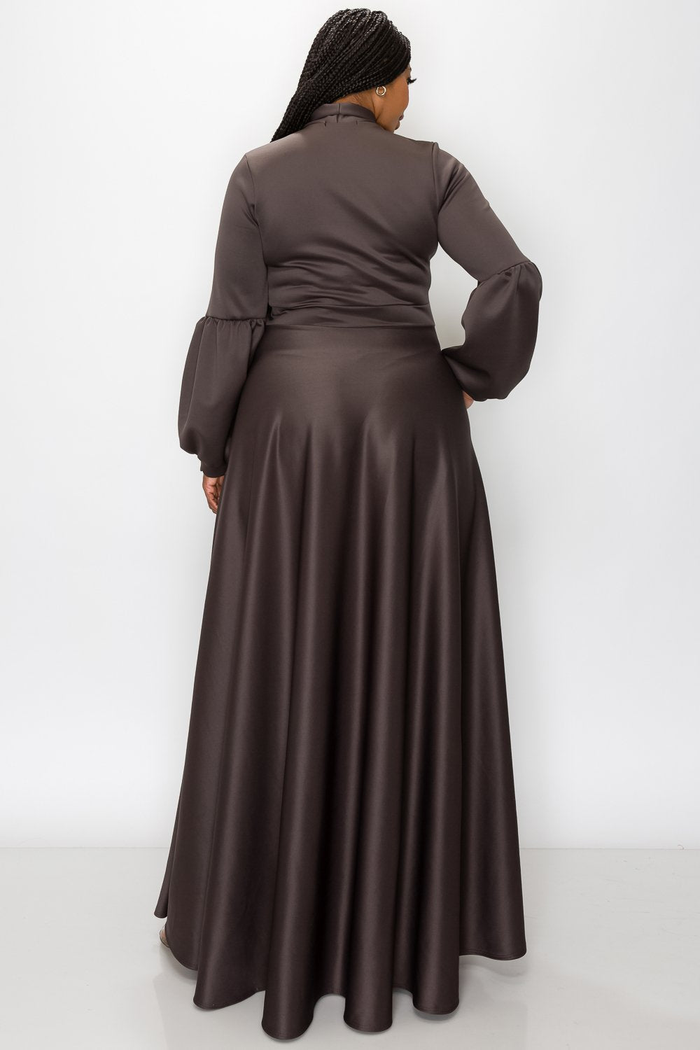 Woman wearing a long brown dress against a white background