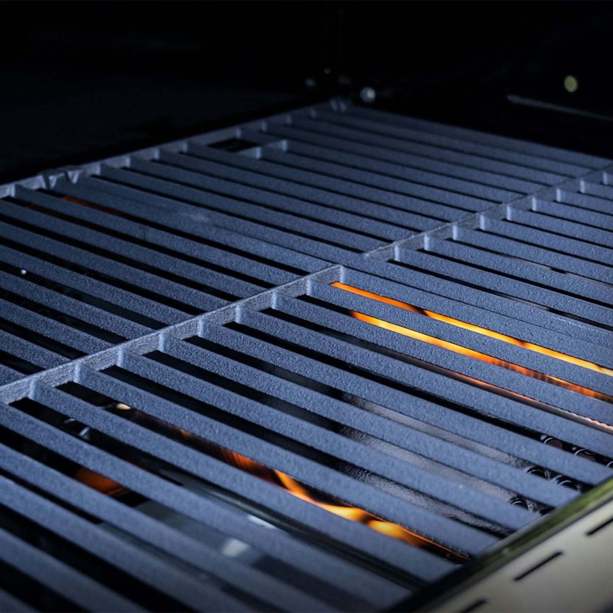 Grill grate with visible flames on a dark background