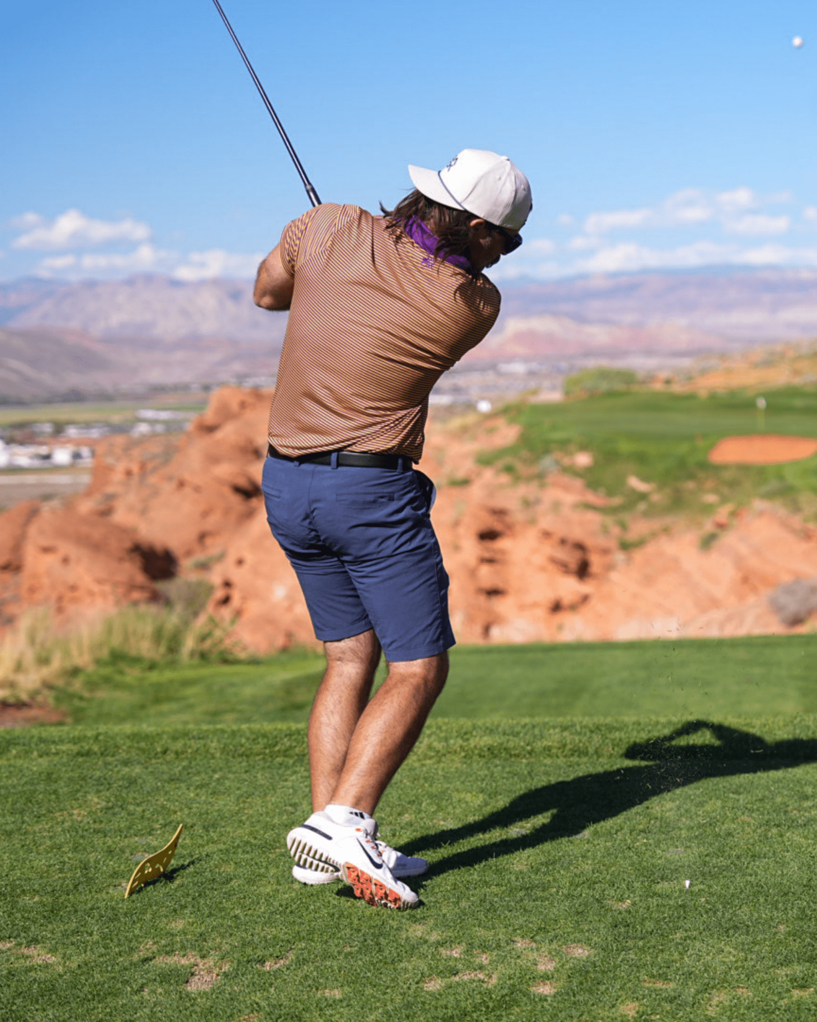 Person playing golf on a scenic course with mountains in the background