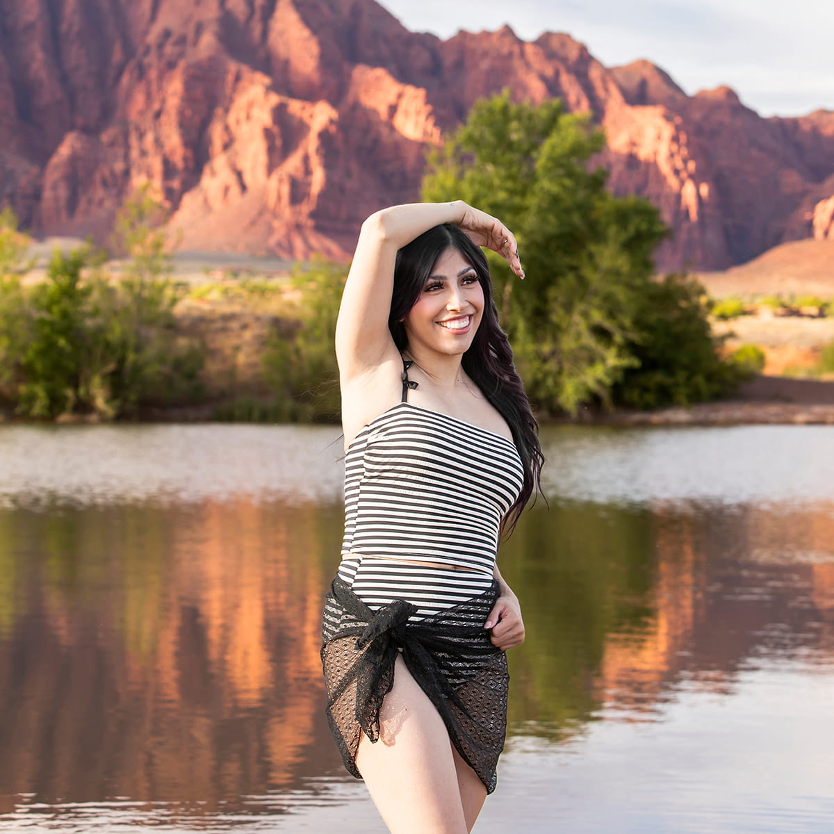Woman posing by a lake with mountains in the background