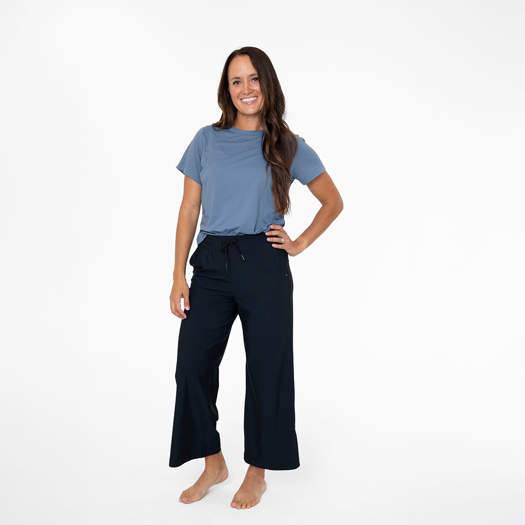 Woman wearing a blue t-shirt and black pants on a white background