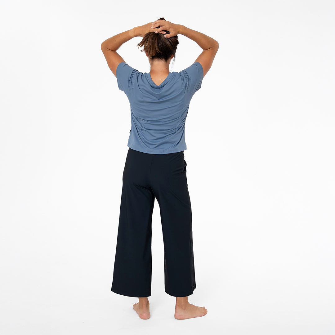 Person wearing a blue top and black pants on a white background