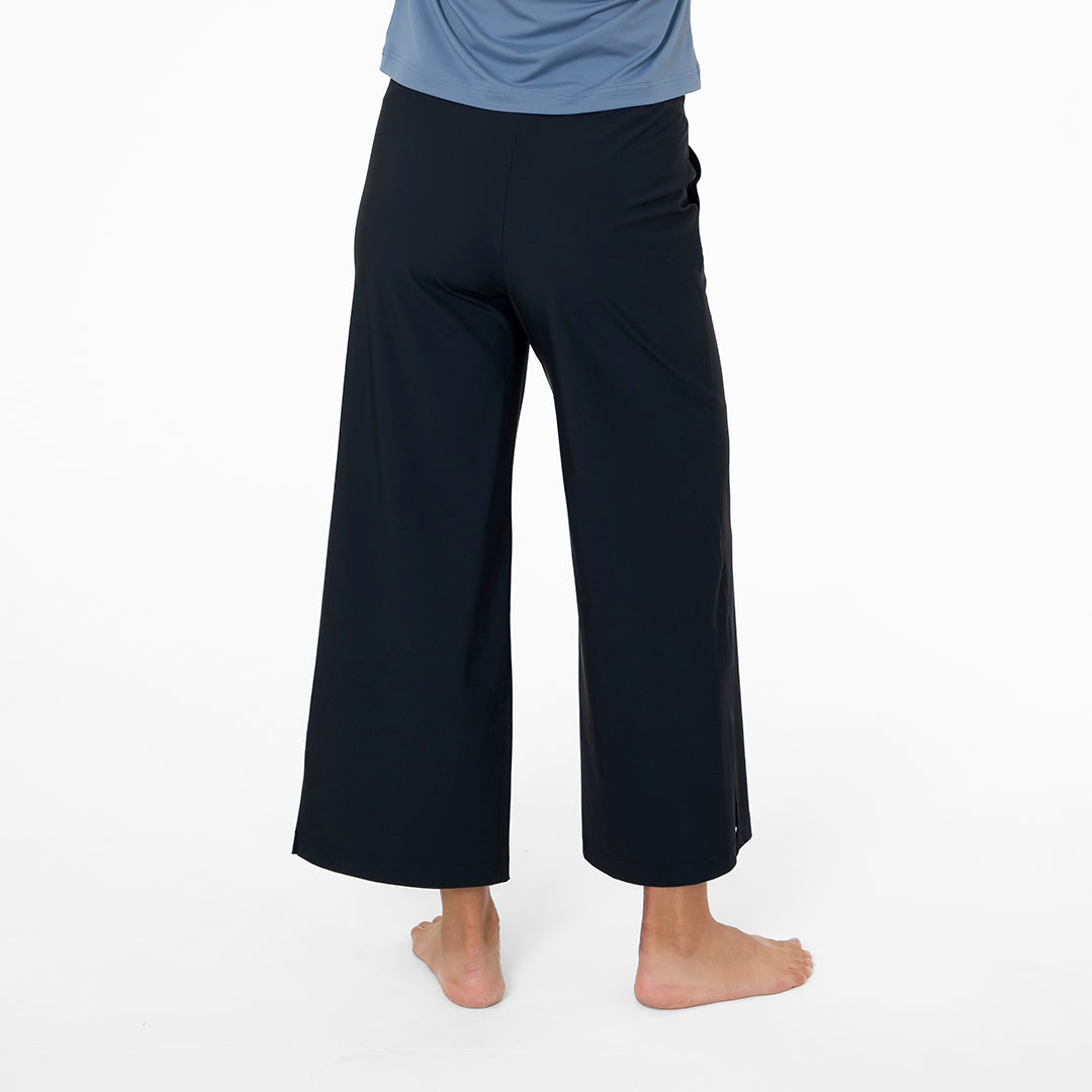 Person wearing black wide-leg pants on a white background