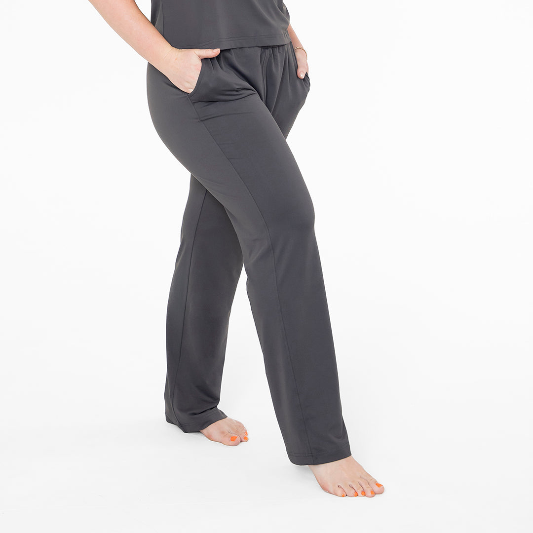 Person wearing dark gray pajama pants on a white background