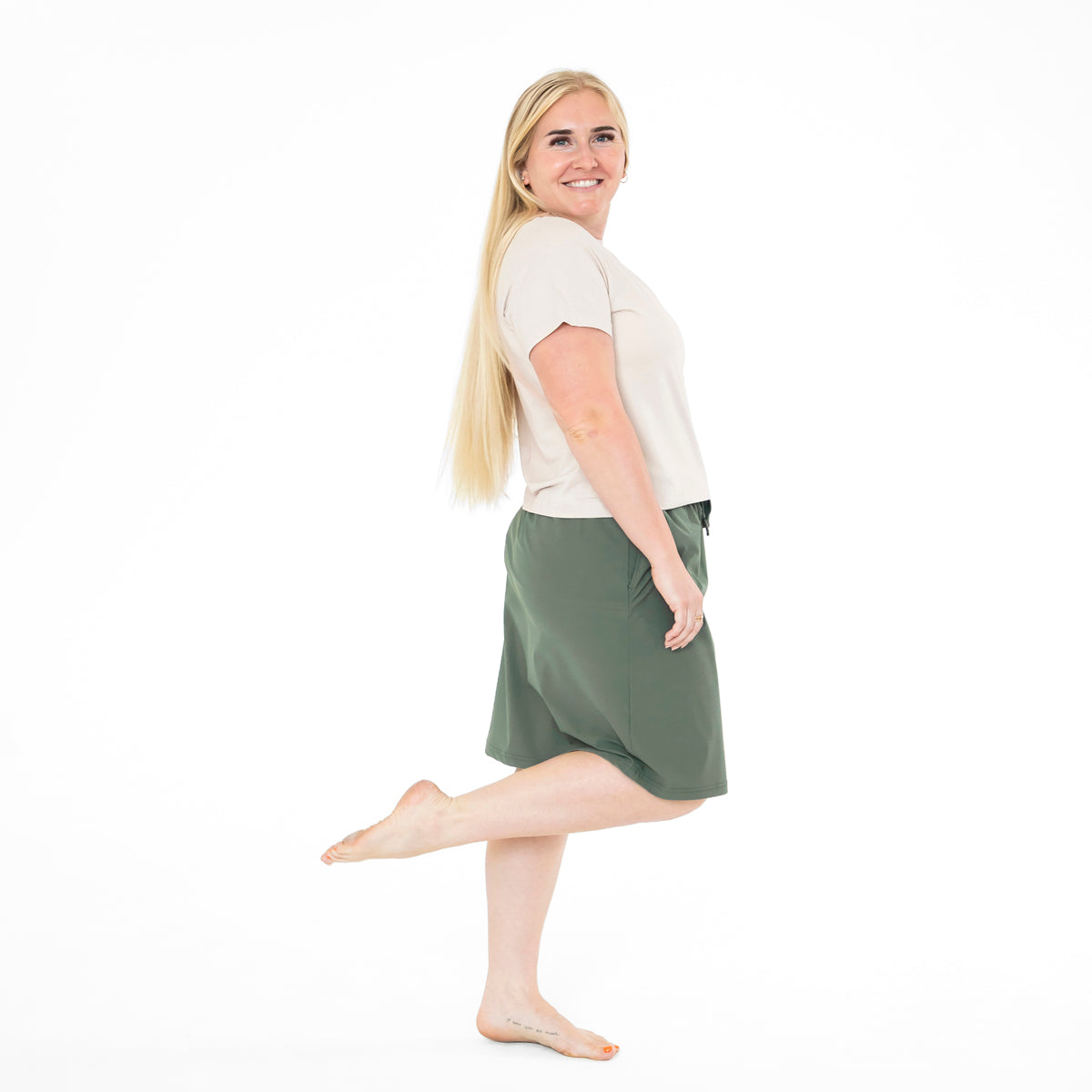 Woman wearing a green skirt and white top on a white background