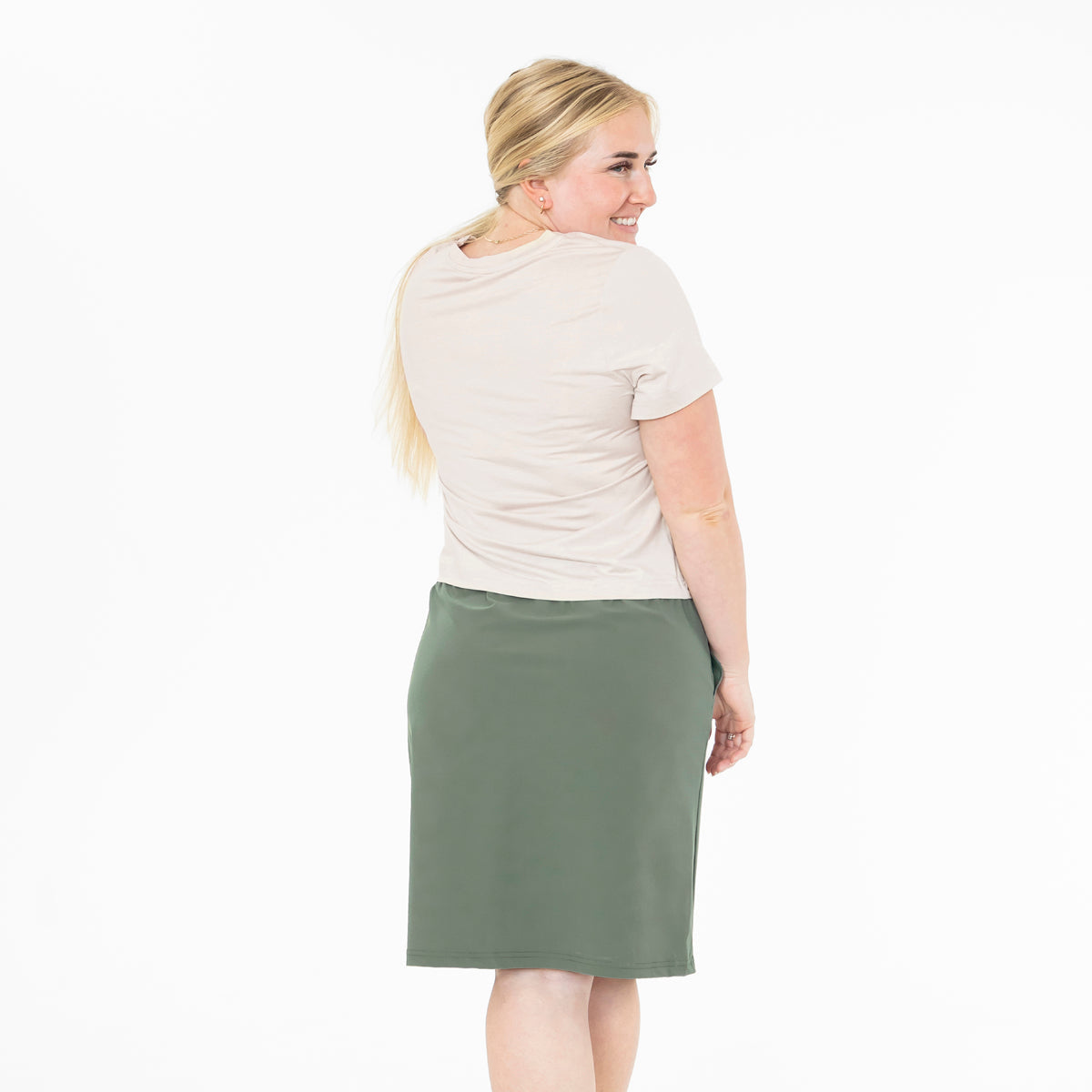 Woman wearing a beige top and green skirt on a white background