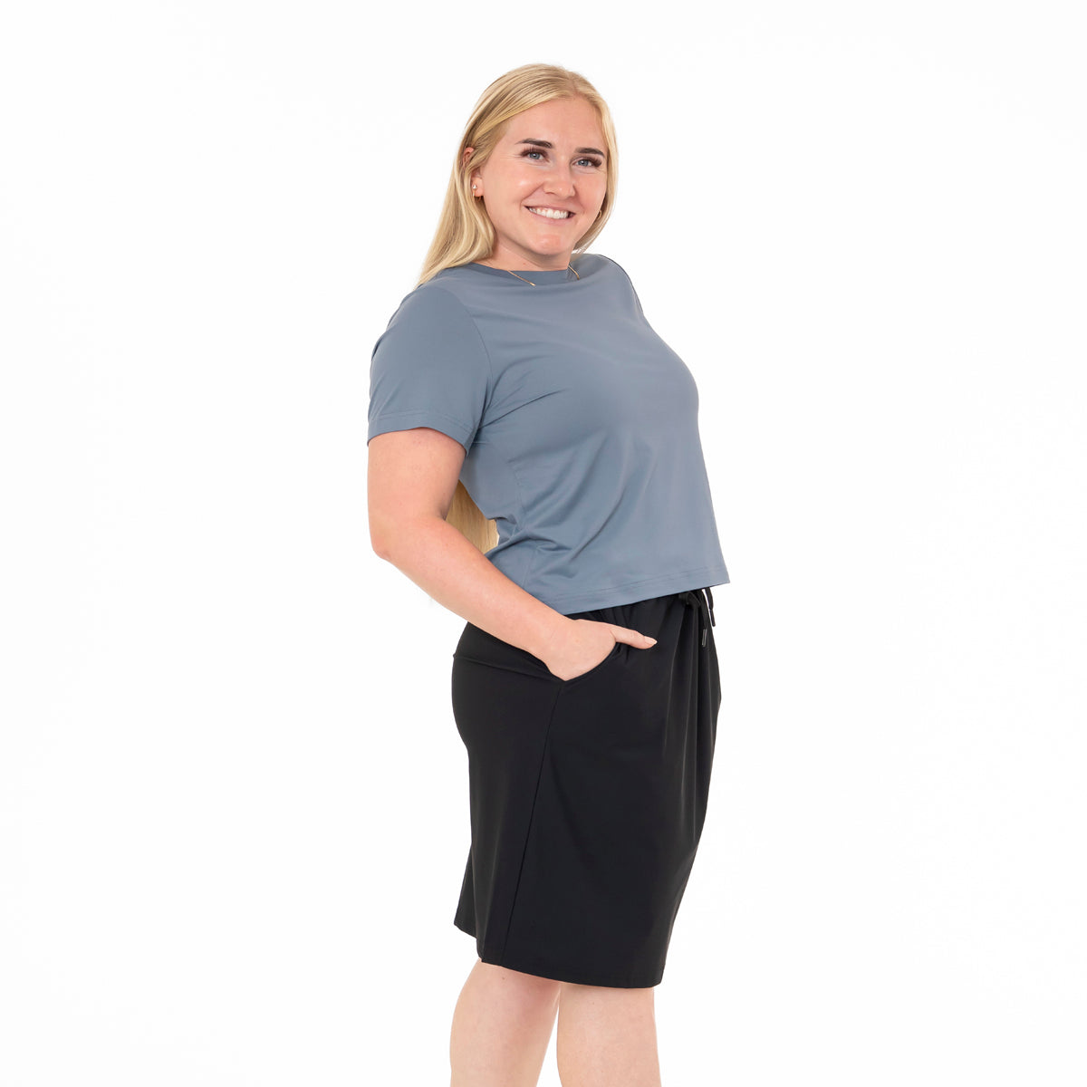 Woman wearing a blue shirt and black shorts on a white background