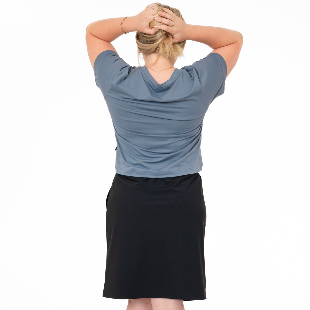 Person wearing a blue shirt and black skirt on a white background