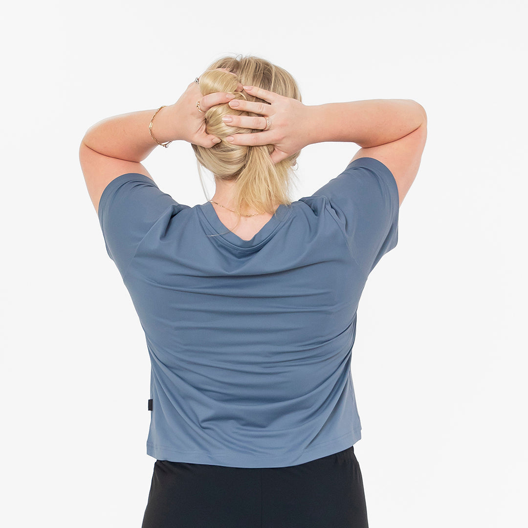 Person wearing a blue shirt with their back to the camera on a white background