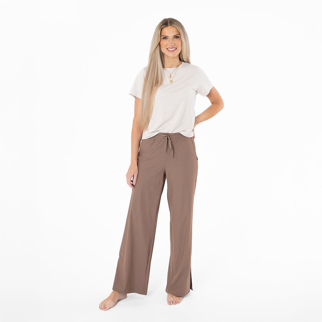 Woman wearing a white top and brown pants on a white background