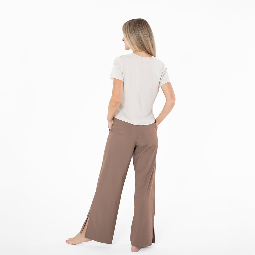 Woman wearing a white top and brown pants on a white background