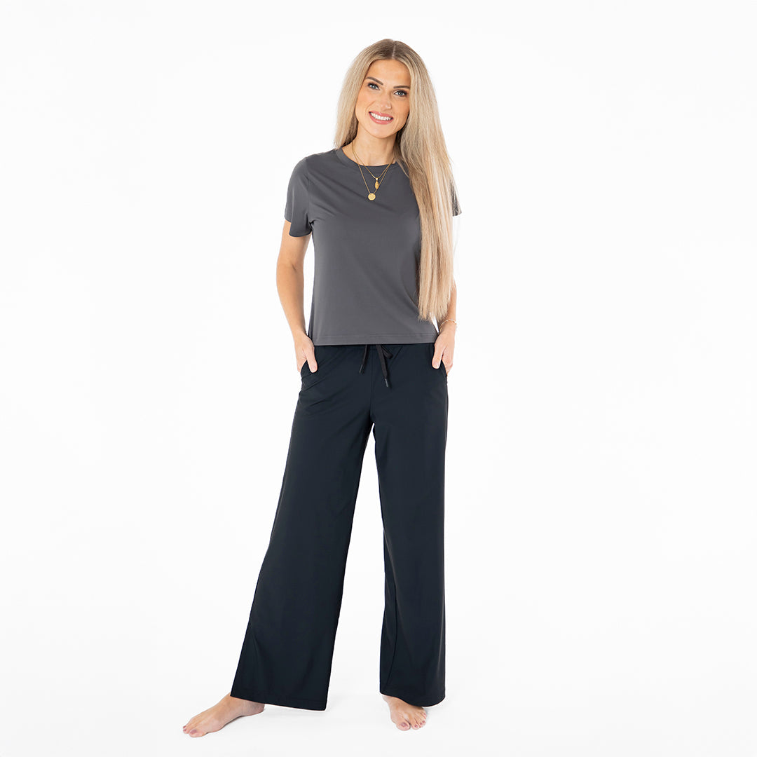 Woman wearing a gray top and black pants on a white background