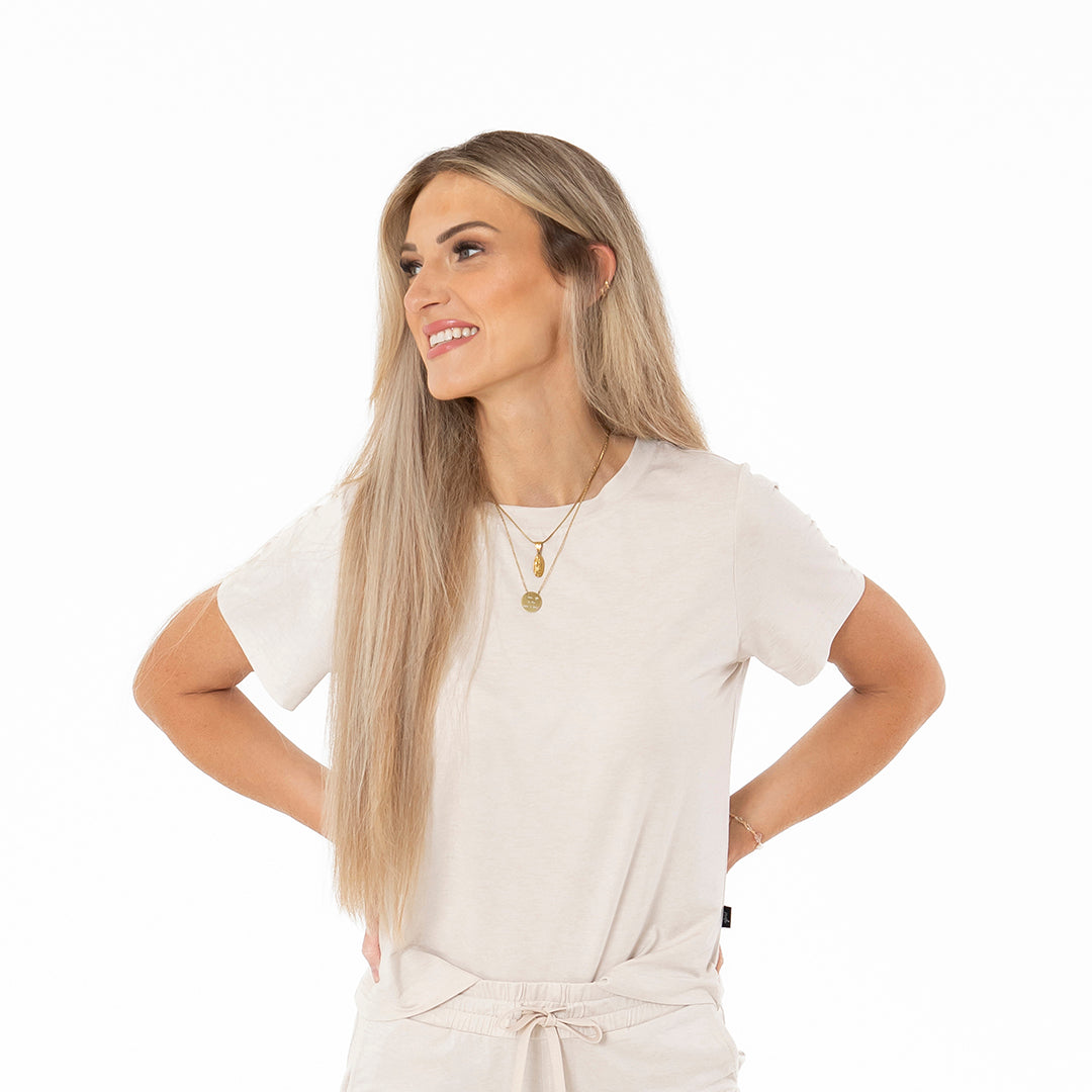 Woman wearing a white t-shirt and beige pants on a white background