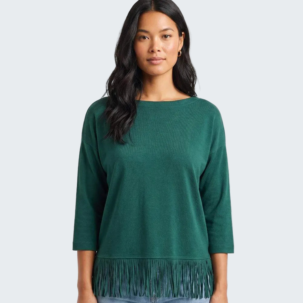 A woman modeling a dark green knit sweater with three-quarter sleeves and a fringe hem, paired with light blue jeans against a plain white studio background.