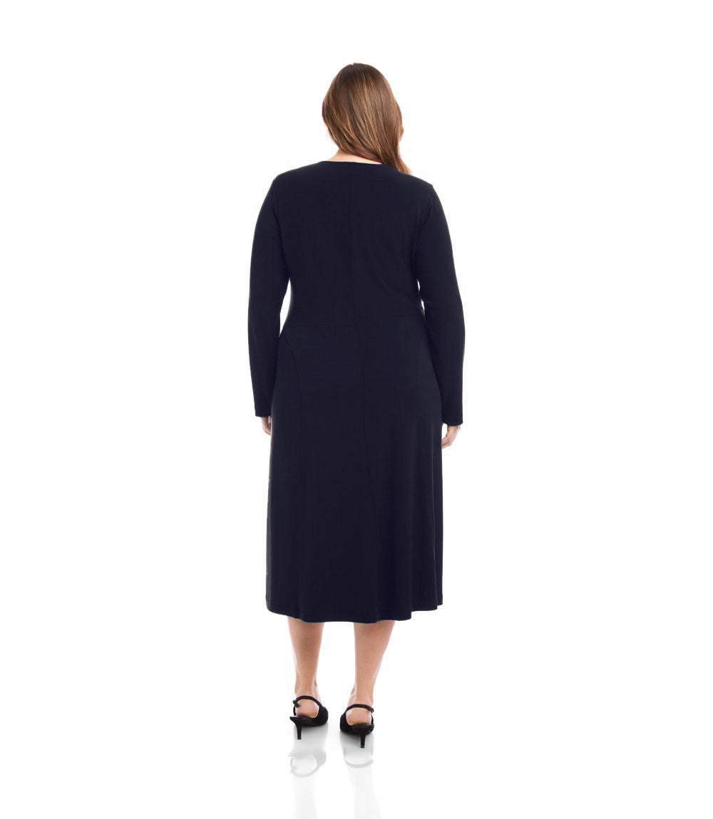 A woman viewed from the back wearing a long-sleeve black midi dress and black heels, standing against a plain white studio background.