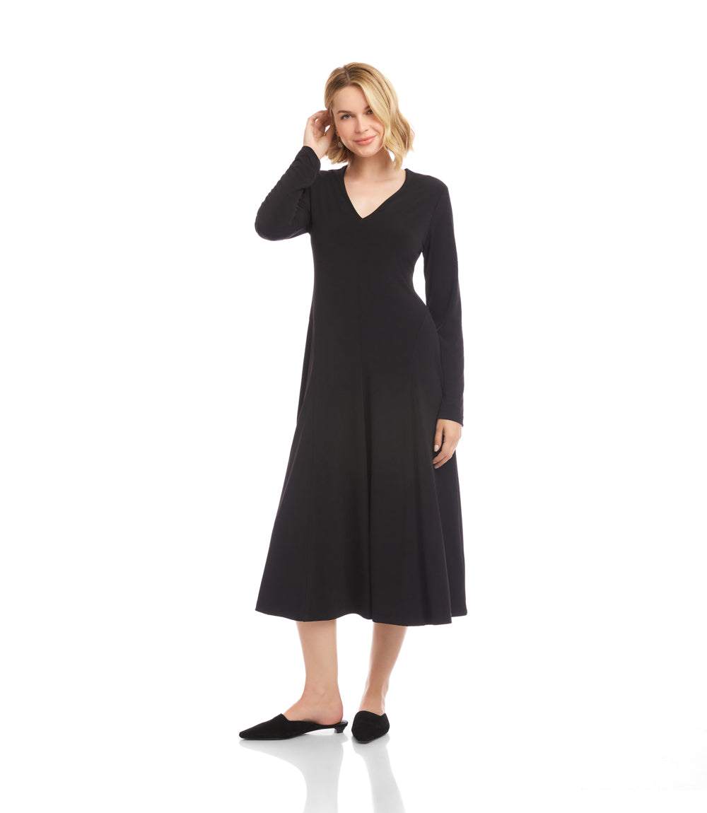 A woman modeling a long-sleeve black midi dress with a V-neckline, shown against a plain white studio background.