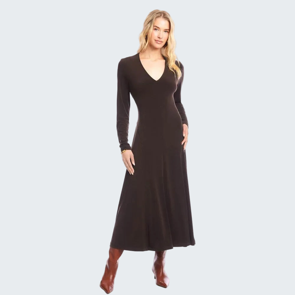 A woman modeling a long-sleeve, V-neck maxi dress in dark brown, paired with brown ankle boots, against a solid white studio background.