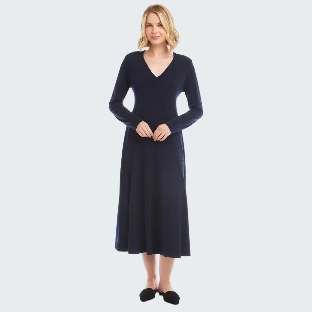 A woman modeling a long-sleeve, V-neck, knee-length knit dress in dark navy blue, standing against a solid white studio background.