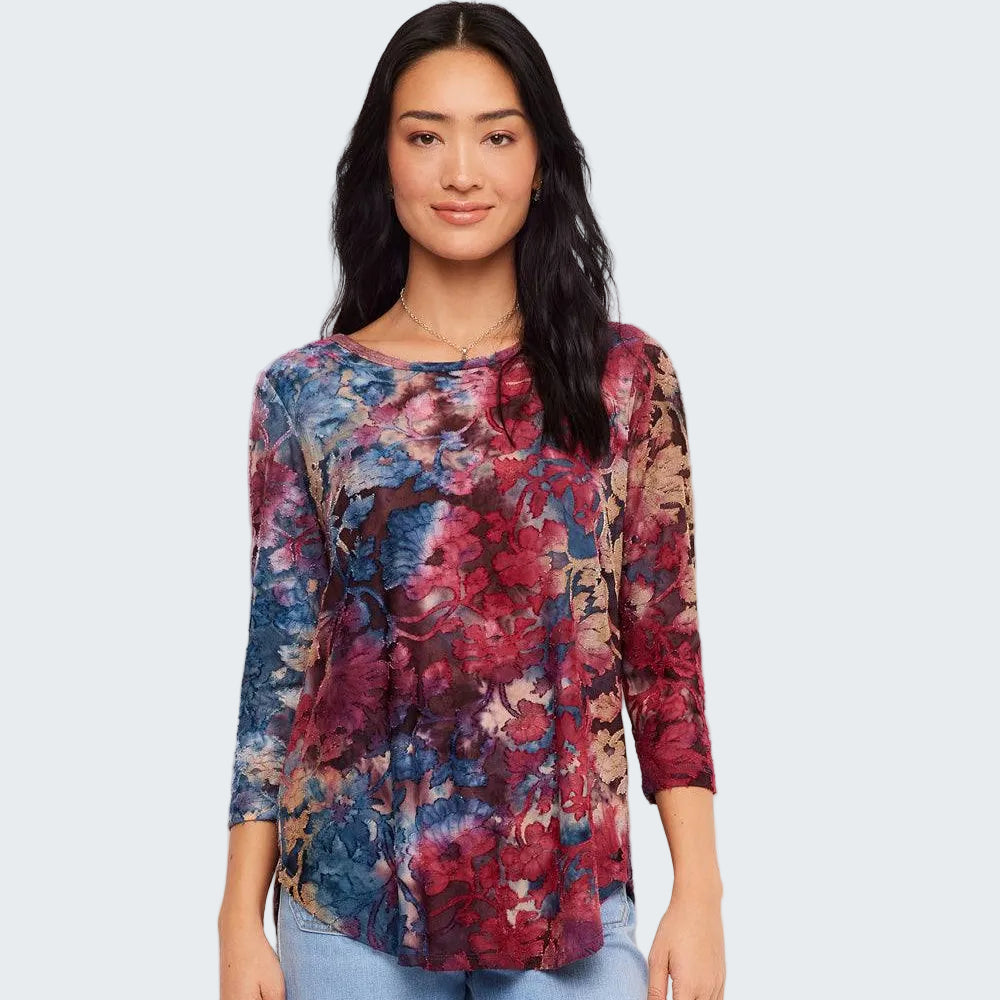 A woman modeling a three-quarter sleeve top with a multicolor floral print in shades of red, blue, and beige, paired with light blue jeans against a plain white background.