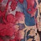 A close-up of a textured surface featuring a dense, abstract pattern of red, blue, and purple tones with a painterly, distressed finish.