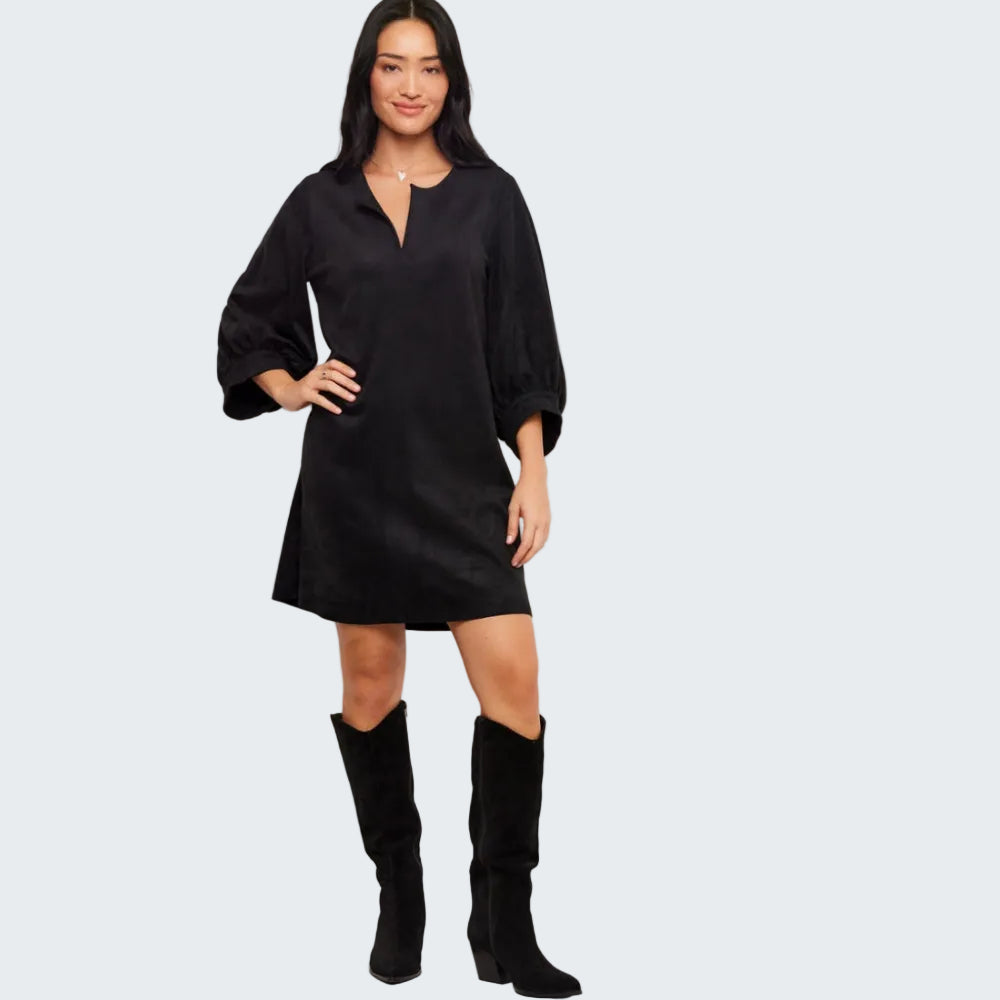 A woman modeling a black short-sleeve mini dress with a split neckline and wide sleeves, paired with black knee-high boots, against a plain white studio background.