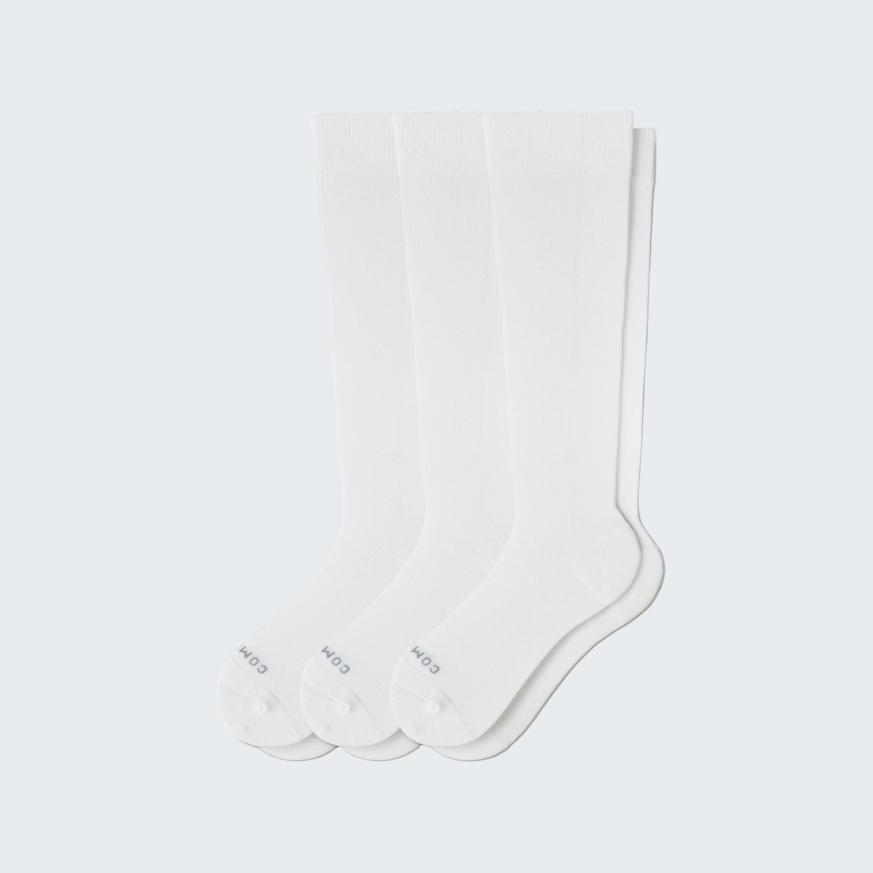 Three pairs of white socks on a light gray background