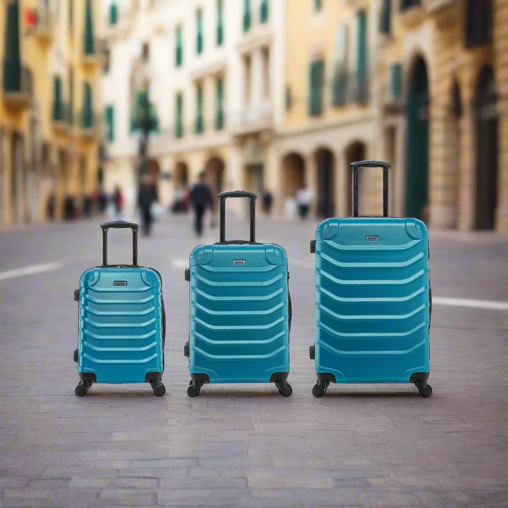 Three turquoise suitcases of different sizes on a city street.