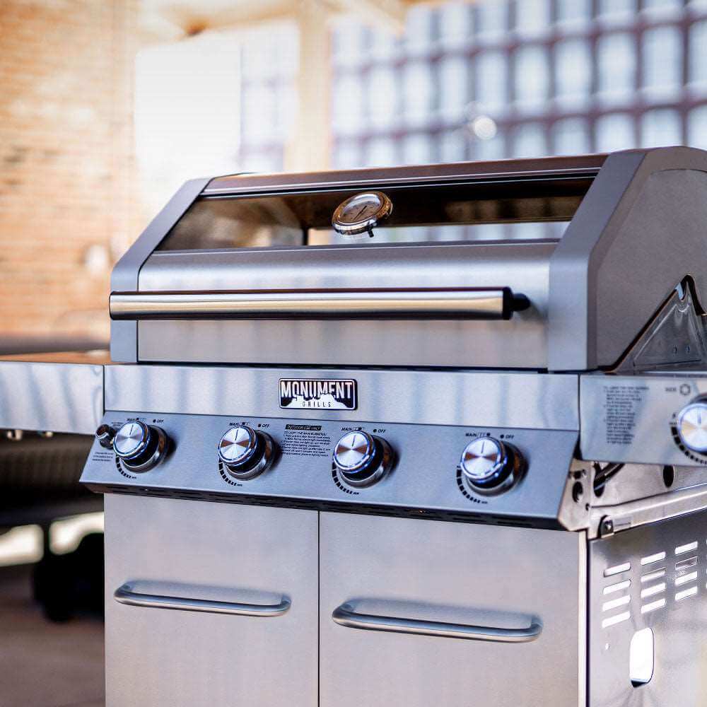 Stainless steel grill with 'Monument' branding in an outdoor setting