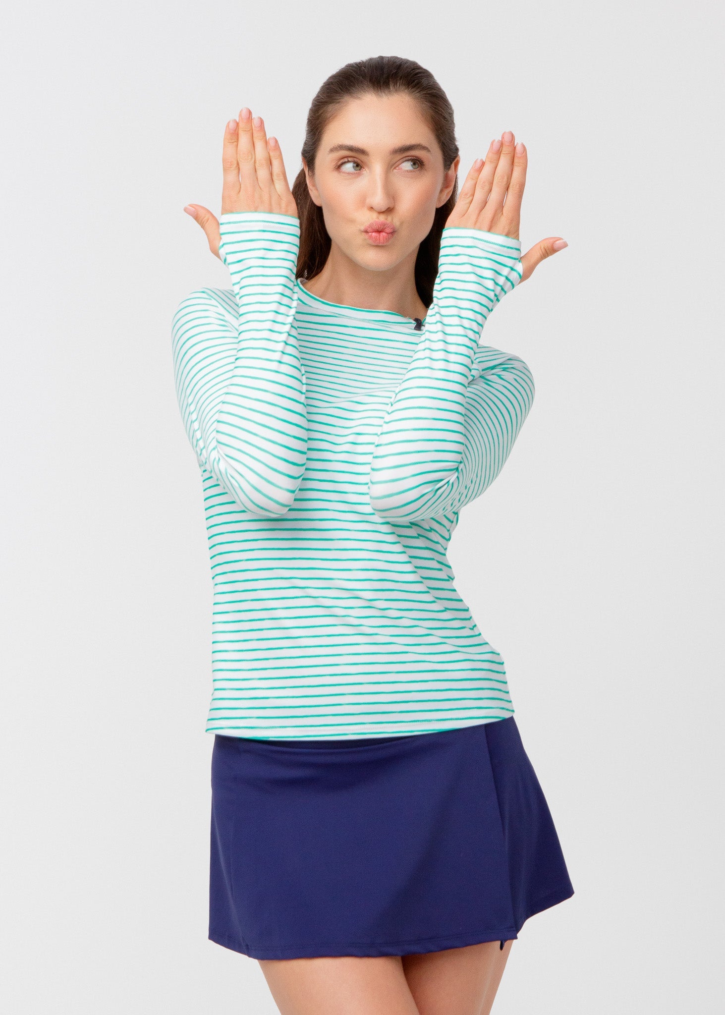 Woman wearing a striped long-sleeve shirt and blue skirt on a light gray background