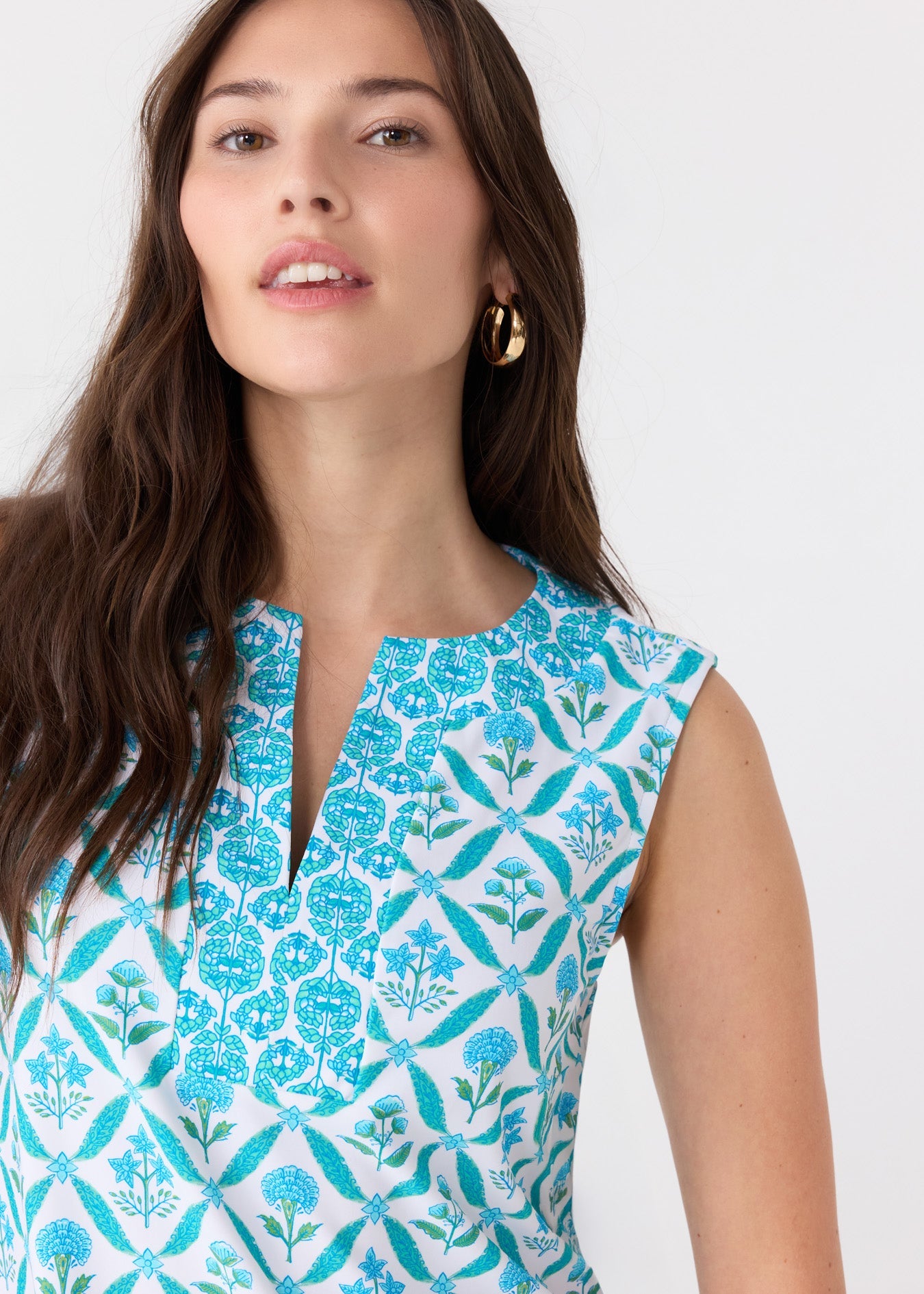 Woman wearing a sleeveless top with blue floral pattern on a white background