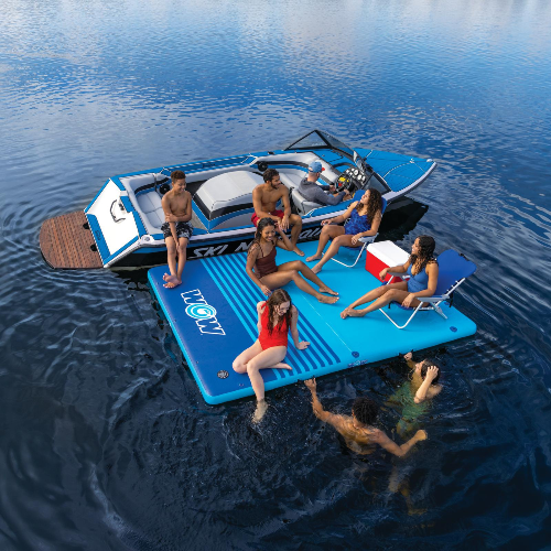 Group of people on an inflatable water mat and boat on a lake