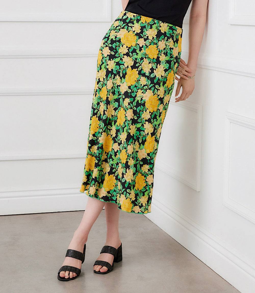 Person wearing a floral skirt with yellow flowers on a plain background