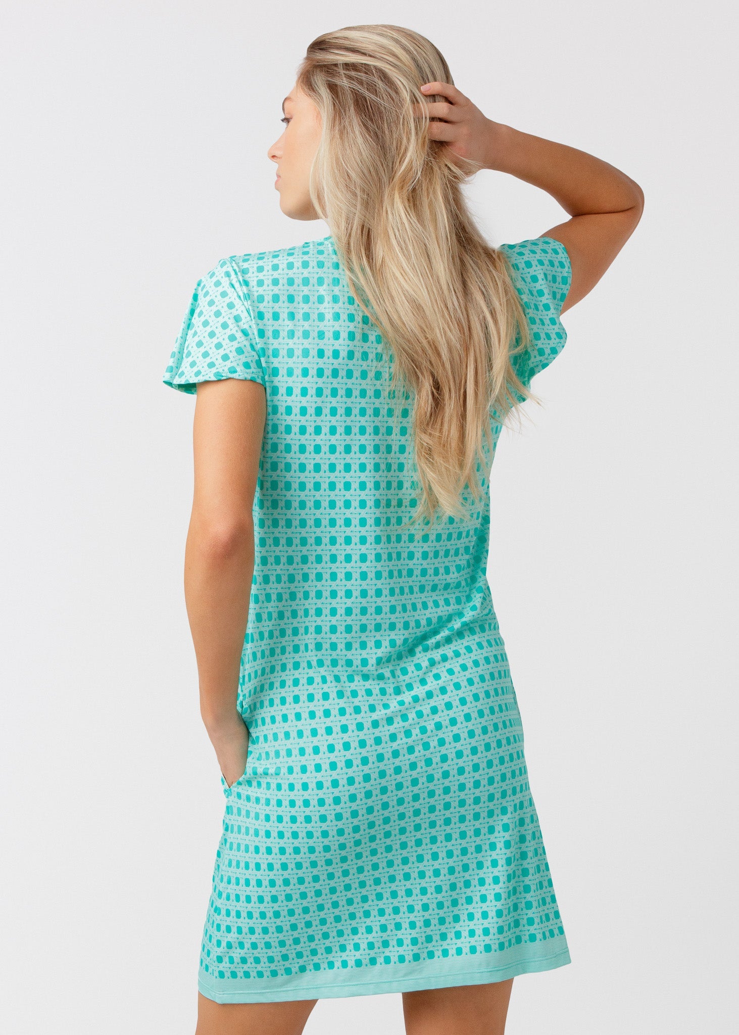 Woman wearing a turquoise patterned dress against a white background