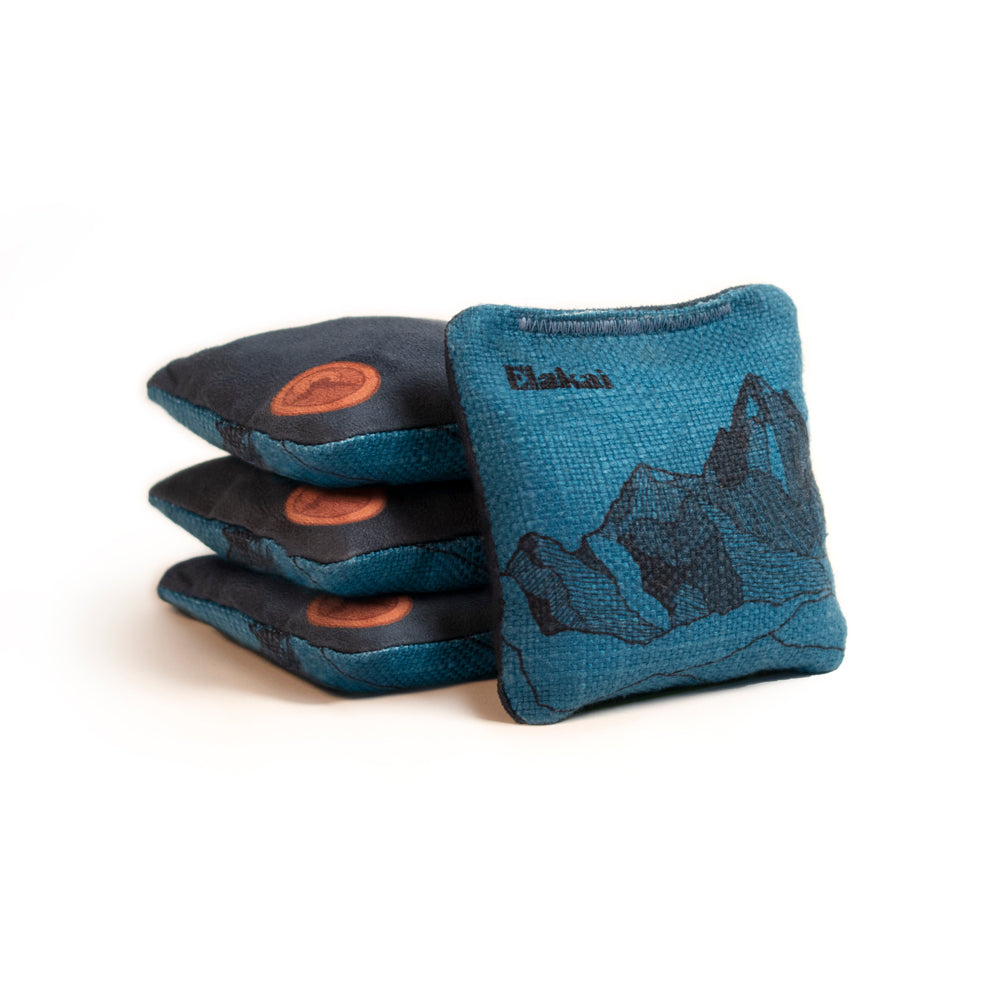 Set of blue cornhole bags with mountain design on a white background