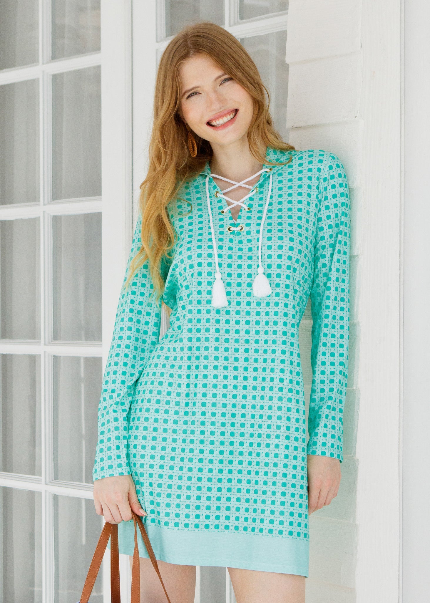 Woman wearing a turquoise checkered dress standing indoors.
